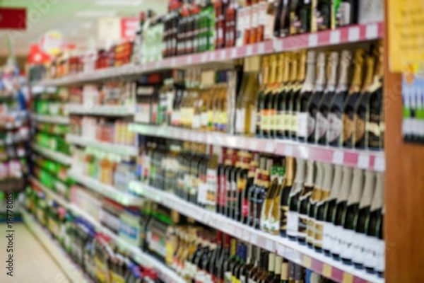 Fototapeta Shelf with beer bottles in a supermarket, blur
