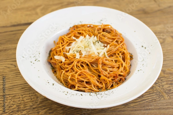 Fototapeta Plate of delicious spaghetti Bolognaise or Bolognese with savory minced beef and tomato sauce garnished with parmesan cheese and basil, overhead view.