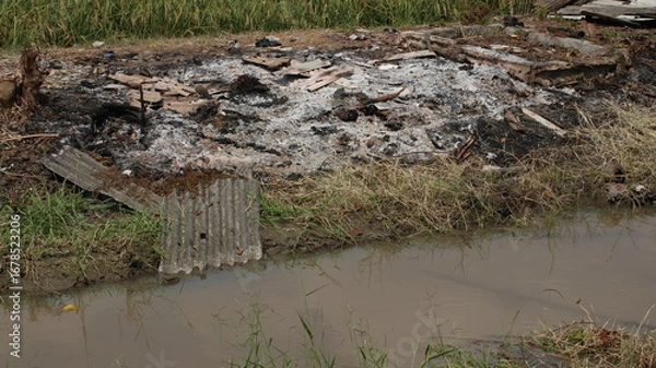 Fototapeta buildings that were burned and reduced to ashes beside the river near the rice fields