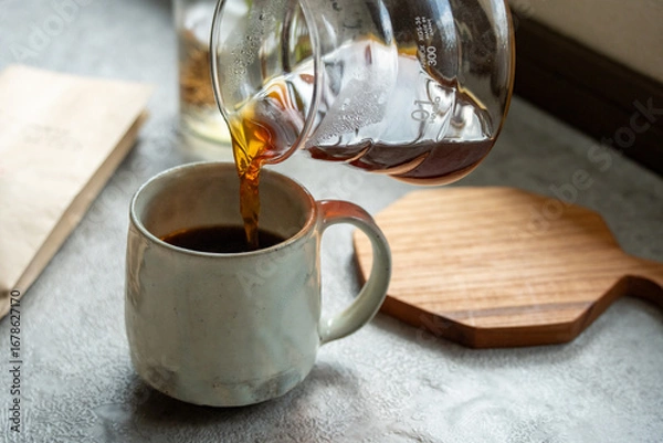 Obraz 光と影の中でコーヒーをカップにそそぐ