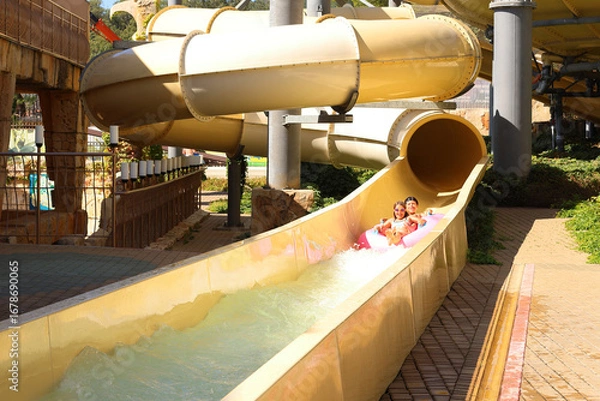 Fototapeta Splashing Fun: Water Adventure. children joyfully riding a water attraction at an amusement park.