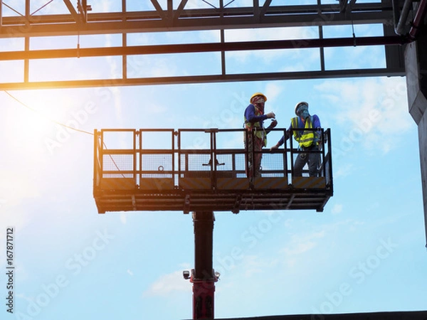 Obraz construction worker at construction site using lifting boom machinery