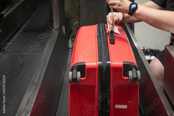 Fototapeta Baggage tagging by airline staff before luggage dispatch