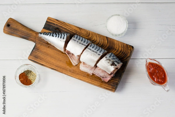 Fototapeta Raw mackerel fish on a cutting board, cooking fish with salt, spices and sauce
