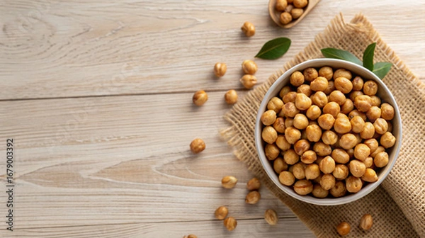 Fototapeta Healthy roasted chickpeas in bowl and on table for delicious vegan snack or nutritious meal prep