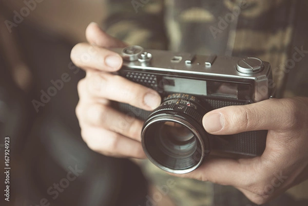 Fototapeta Vintage photo camera in the hands of man, soft focus.