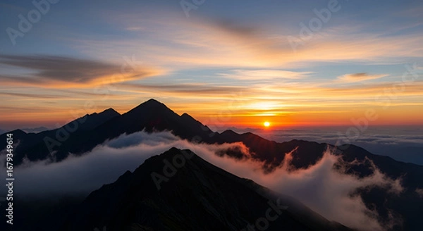 Fototapeta Stunning mountain range silhouette meets a vibrant sunrise, painting the sky with breathtaking warm colors and a mystical fog rolling through the peaks