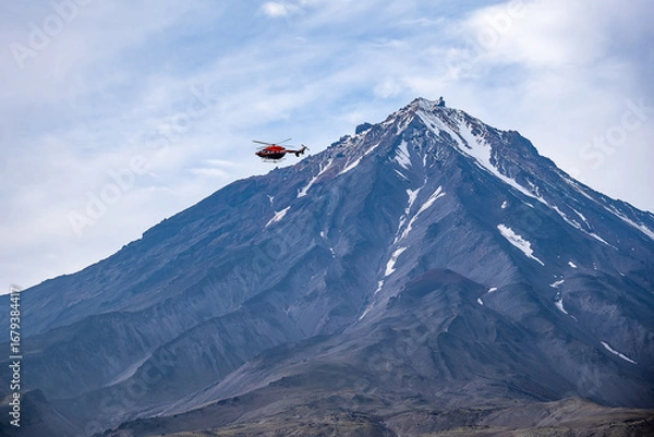 Fototapeta Red helicopter flying with Avachinskaya Sopka volcano in the background. Illustration of adventure and exploration in the picturesque Kamchatka landscape. Russia, Kamchatka - August 28, 2024