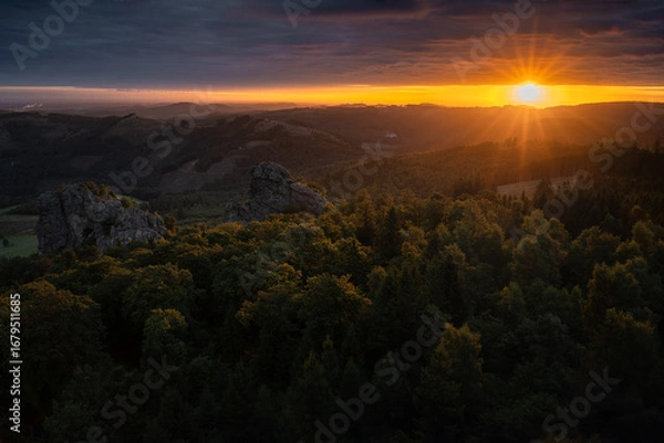 Fototapeta Dramatic sunrise in Germany's Sauerland region. The Bruchhausen Steine ​​rocks and forest are illuminated by golden rays of sunlight.