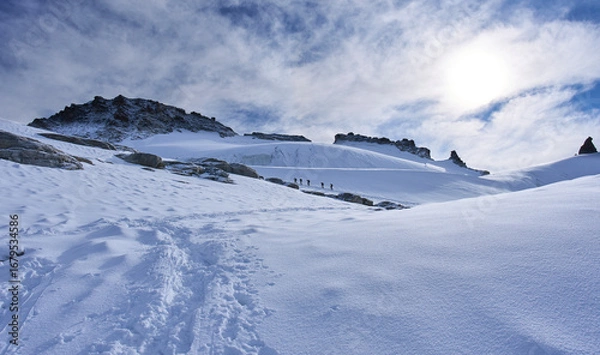 Fototapeta Gran Paradiso National Park, Italy. Climbers on the way to the summit of the mount Gran Paradiso from the Refuge Victor-Emmanuel II. A lot of snow covered a glacier. Sunny chilly day.
