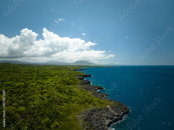Obraz A long, sandy beach stretching along the coast, lined with lush green forest and resort-like buildings further away. A wide, stunning bay with vibrant blue and turquoise water, where several boats are