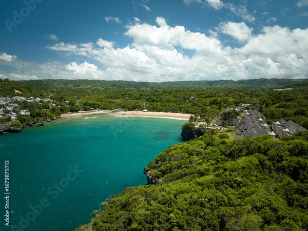 Obraz A long, sandy beach stretching along the coast, lined with lush green forest and resort-like buildings further away. A wide, stunning bay with vibrant blue and turquoise water, where several boats are