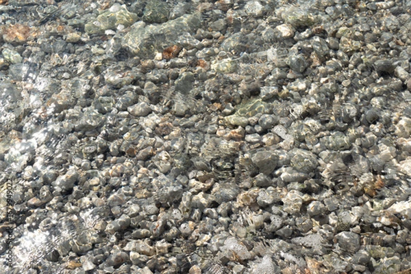 Fototapeta Pebbles and Rocks on a Beach with Clear Transparent Sea Water in Croatia. texture
