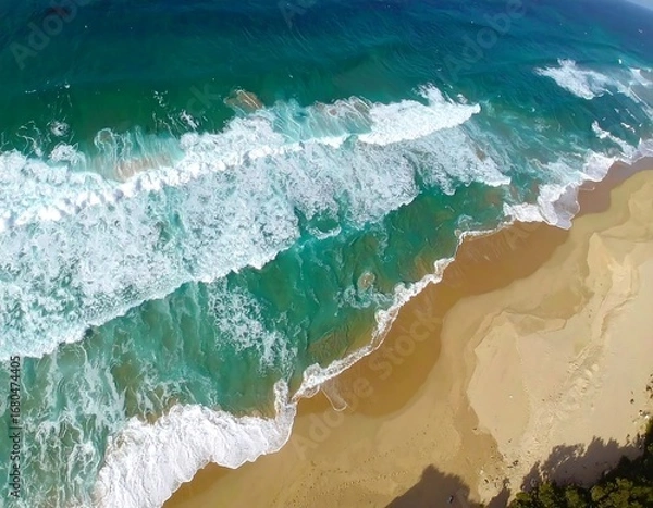Obraz High-angle view of turquoise waves crashing on a sandy beach, showcasing the interplay of water and land.
