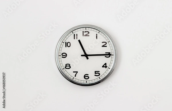 Fototapeta White Clock hanging on a white wall showing time 11:15