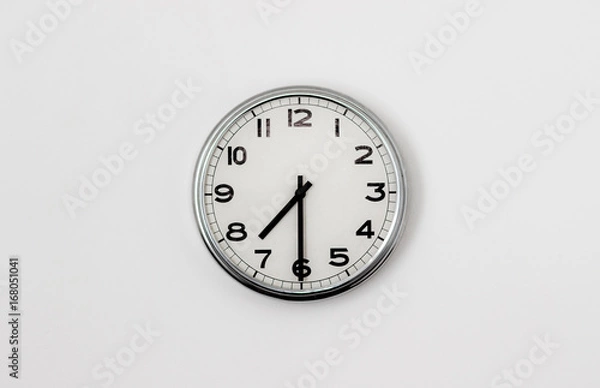 Fototapeta White Clock hanging on a white wall showing time 7:30