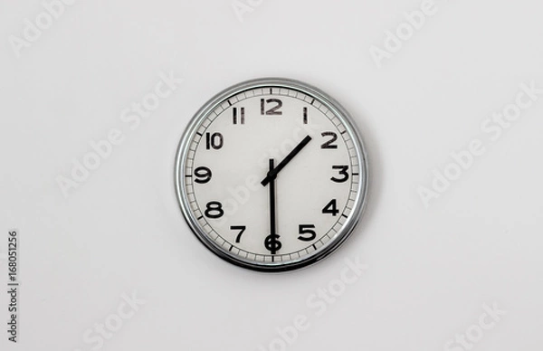 Fototapeta White Clock hanging on a white wall showing time 1:30