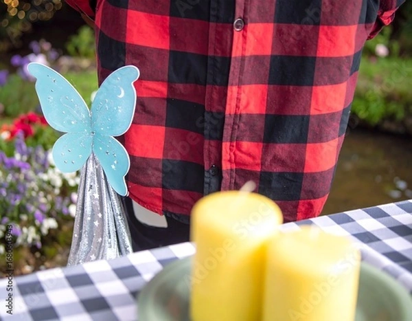 Fototapeta Festive outdoor scene with checkered tablecloth, candles, and whimsical butterfly decoration