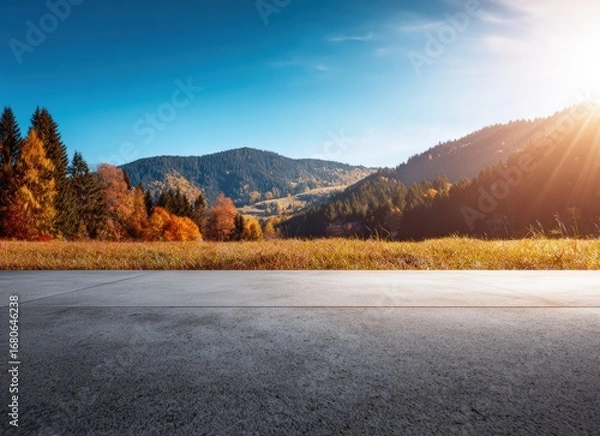 Fototapeta Asphalt road leading through a beautiful autumn landscape with colorful trees and mountains at sunset
