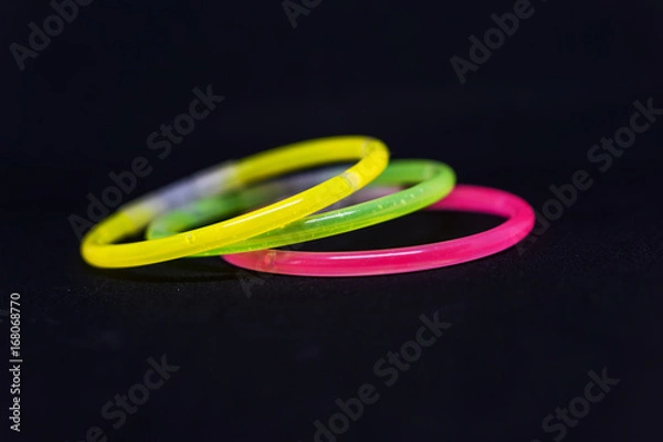 Fototapeta Trendy color, neon bracelets, on black background. Beuty fashion concept. Shallow depth of focus.