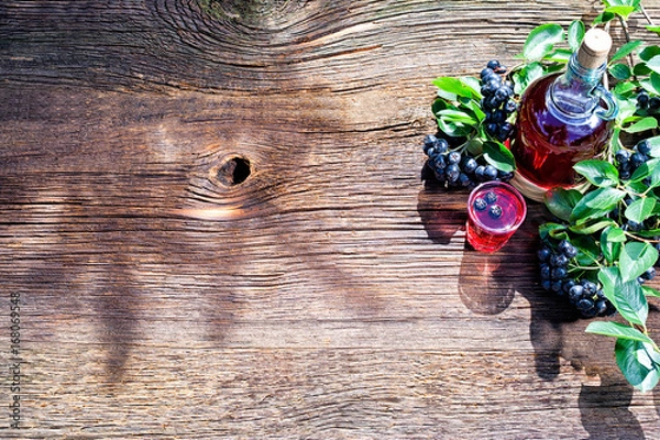 Fototapeta A glass of tincture of chokeberry. Free space for your text. Wooden background.