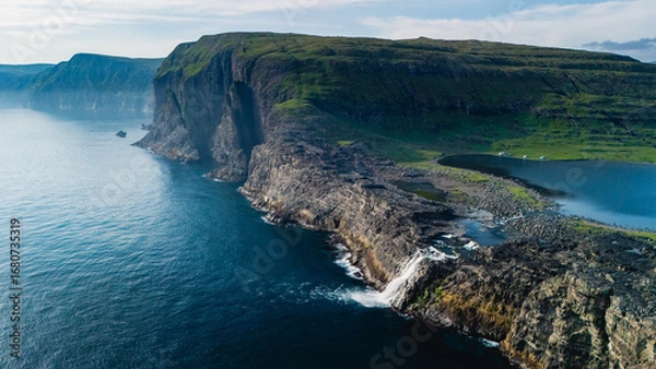 Fototapeta Majestic cliffs and serene waters of the Faroe Islands at golden hour