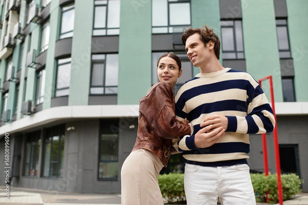 Fototapeta Young couple enjoying a joyful moment outside a modern building in the city