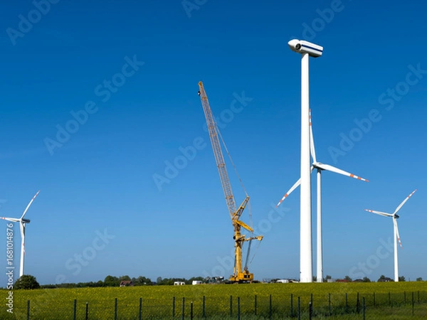 Obraz Wind turbines under maintenance. A crane operationg on removed blades.