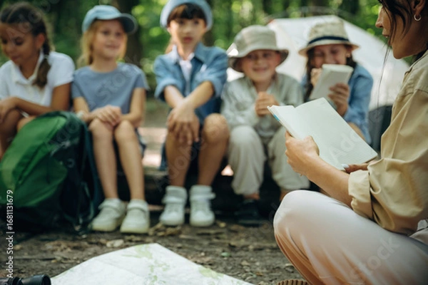 Obraz It's the story time. Woman is doing tour for group of kids in the forest