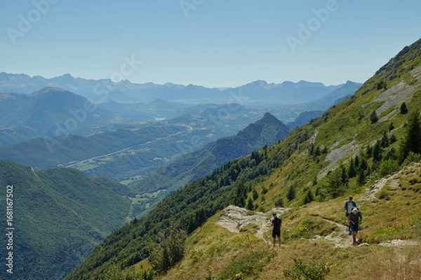 Obraz Scenic hiking trail with hikers enjoying panoramic alpine mountain landscape on clear summer day