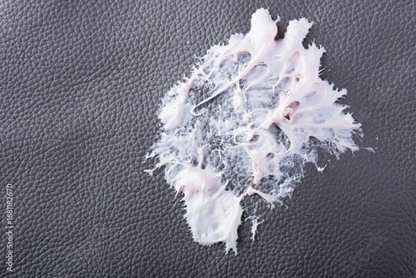 Fototapeta Chewing gum has become stuck to a dark textured surface, showing its stretching and gooey consistency. The leather surface shows intricate texture as the cleaning care. Daily stains concept