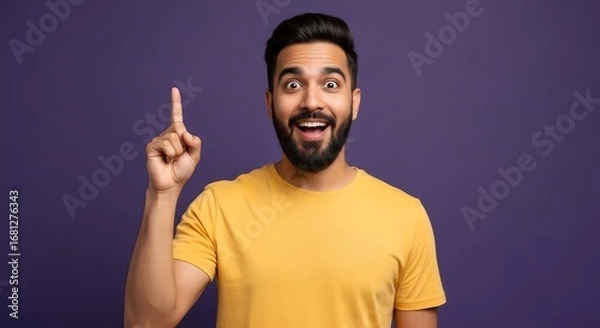 Fototapeta Man in yellow shirt pointing upwards with excited expression against a purple background idea moment