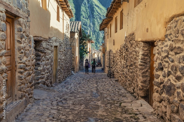 Fototapeta Traditional narrow alleyway with ancient Inca stone walls and cobblestone pavement in the historic town of Ollantaytambo, Peru.