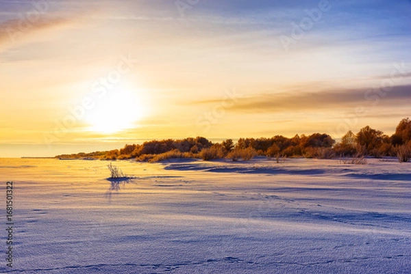 Fototapeta Scenic view of sunset and snow field. Field covered with a snow in cold winter season.