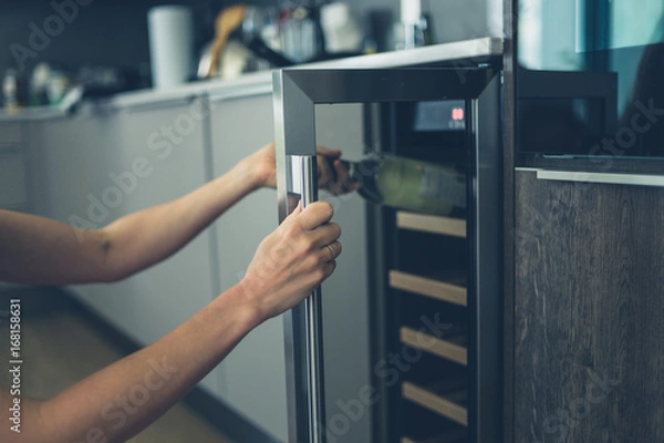 Obraz Woman getting bottle of wine from cooler