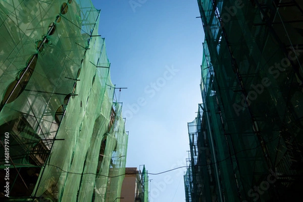 Fototapeta A shot of a building in Alexandria covered in a web of green scaffolding and netting, representing the ongoing urban development of the city
