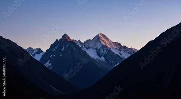 Fototapeta Sunset illuminating snow-capped mountain peaks amidst shadowed valleys in tranquil twilight