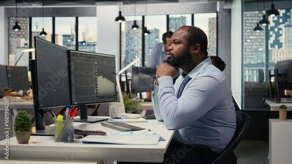 Fototapeta Day trader analyzes stock market price charts, doing thinking, making buy and sell decisions in prop firm office. Man doing brainstorming, placing client orders using trading platform