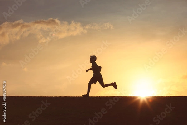 Fototapeta Silhouette of a running child during a serene sunset, evoking energy and freedom
