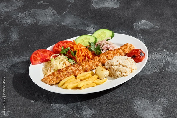 Fototapeta Lule kebab plated with vegetables and rice, bright lighting, overhead composition