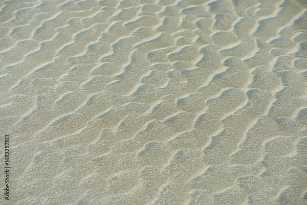 Fototapeta Close-up of rippled sand dunes, showing texture and natural patterns. Uneven sand texture, beach background, top down view. Closeup shot of sand texture on the beach as background.