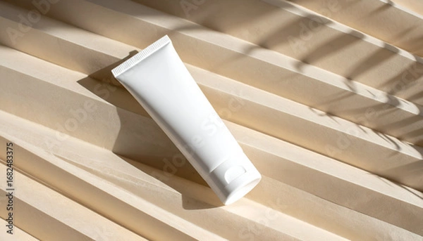 Fototapeta Minimalist product mockup of a white tube on a fluted panel, with dramatic shadows from warm side lighting creating texture and rhythm