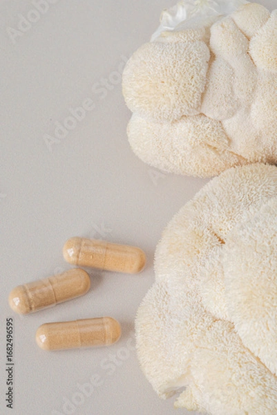 Fototapeta Close-up of lions mane mushroom and herbal supplement capsules on light background. Natural nootropic and medicinal fungi concept. Flat lay composition.