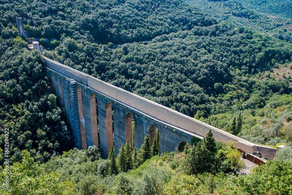 Fototapeta Ponte delle Torri in Spoleto is an ancient Roman aqueduct bridge crossing a deep valley full of trees, creating a picturesque landscape in Umbria, Italy