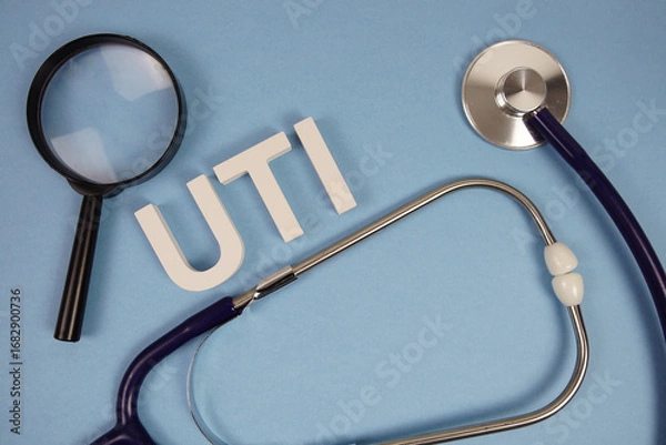 Obraz UTI abbreviation of Urinary Tract Infection alphabet letters with magnifying glass and stethoscope on blue background