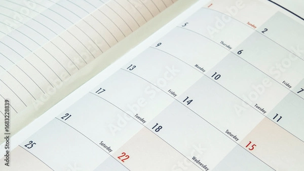 Fototapeta A close-up of an open planner or calendar book showing the dates and days of the week, representing the concept of planning and time management.