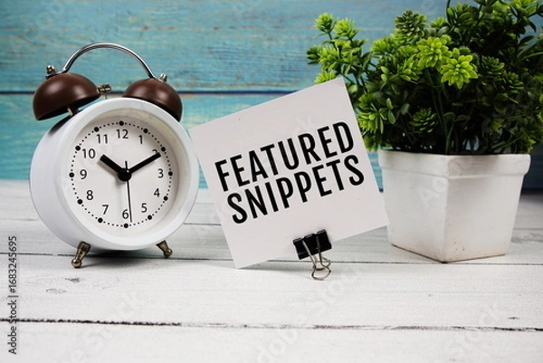 Obraz Featured Snippets text written on paper card with alarm clock on wooden background