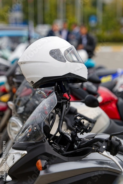 Fototapeta Closeup white moto helmet on motorcycle handlebars against blurred background