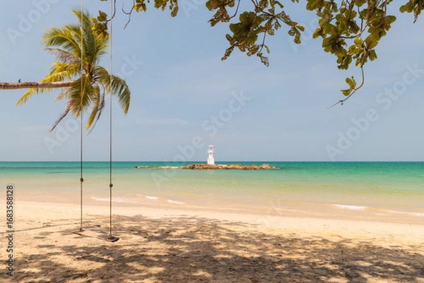 Fototapeta A Lighthouse on the beautiful beach with wooden swing and coconut trees under blue sky in Khao Lak, a destination of tourist in  Phang-Nga province, Southern of Thailand