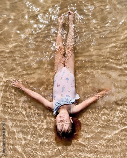 Obraz The girl swims in the water, lying on her back.